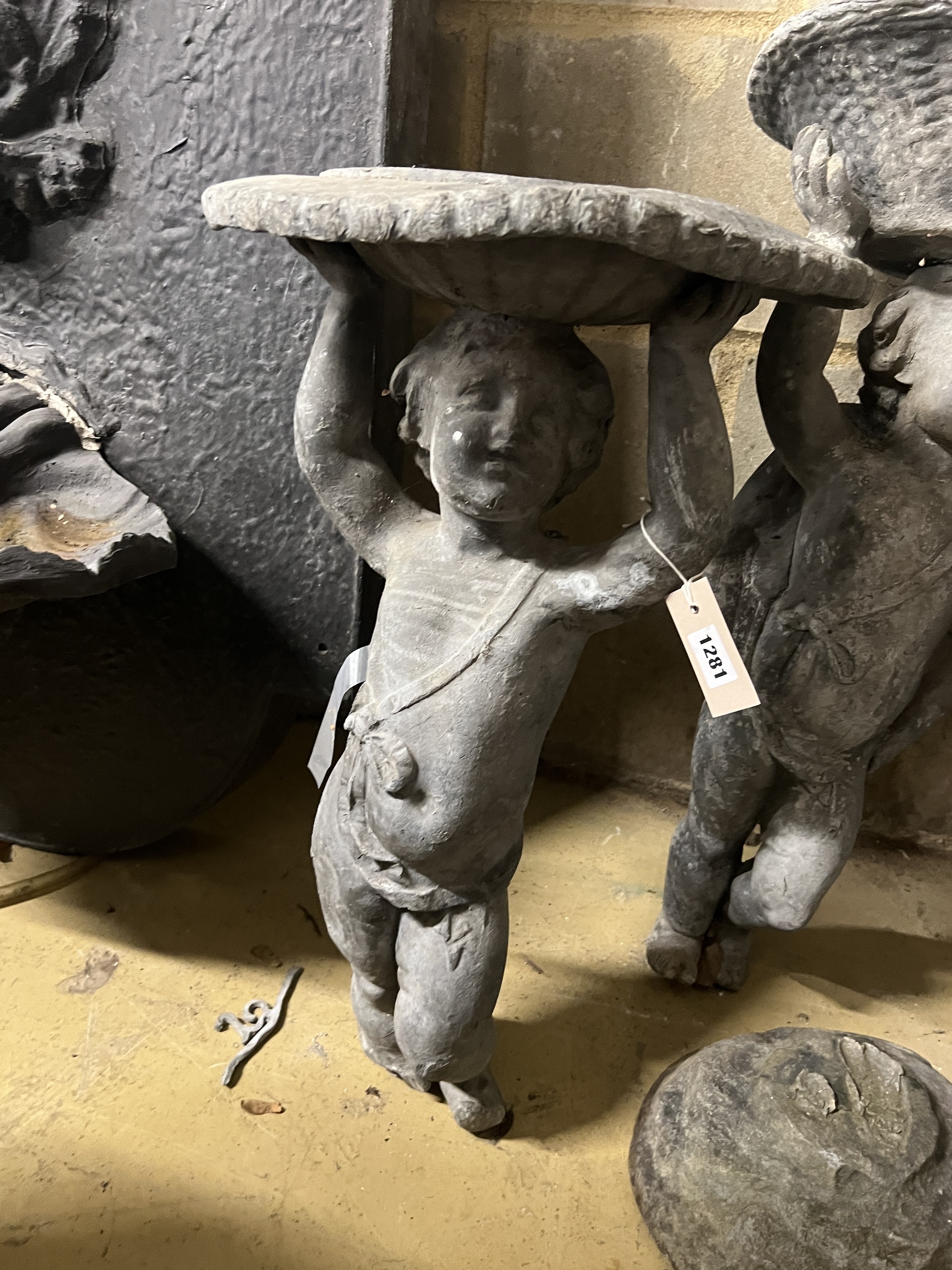 Two Victorian lead garden putto figures, one as a sundial, the other a birdbath, in need of restoration, larger height 69cm